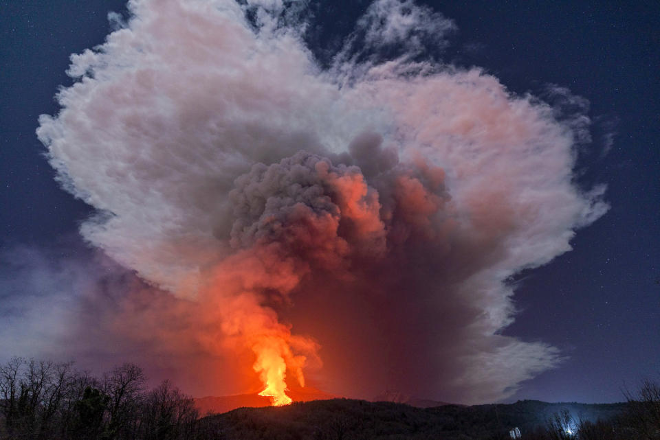 A fiery river of glowing lava flows on the north-east side of the Mt Etna volcano engulfed with ashes and smoke near Milo, Sicily, Wednesday night, Feb. 24, 2021. Europe's most active volcano has been steadily erupting since last week, belching smoke, ash, and fountains of red-hot lava. (AP Photo/Salvatore Allegra)