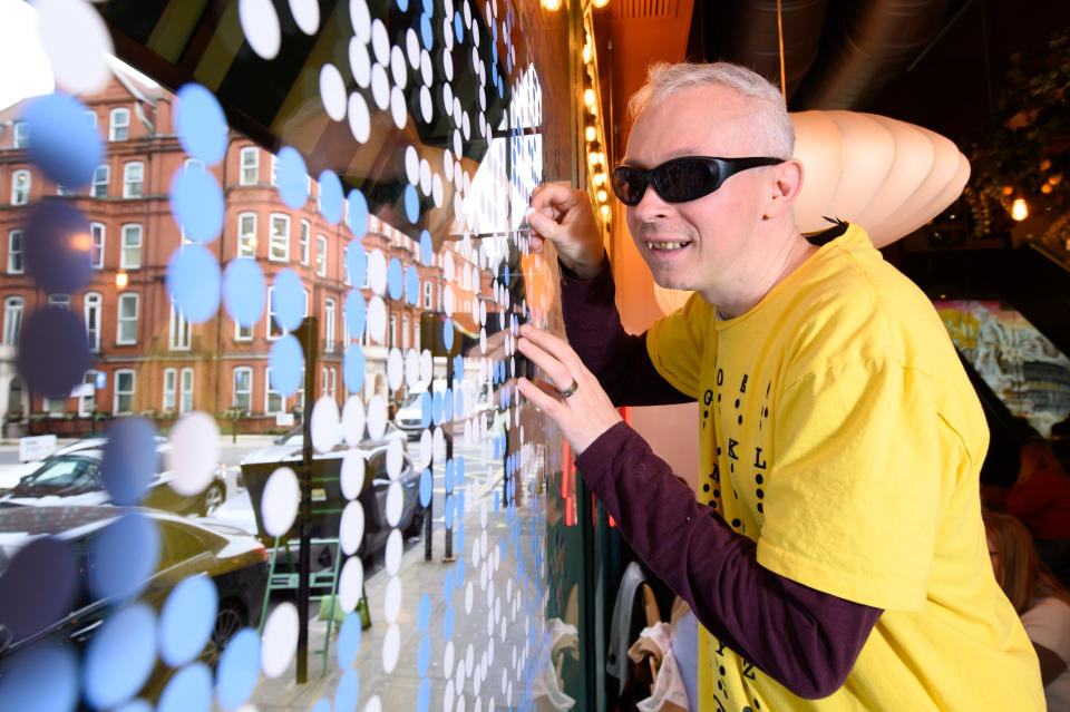 Blind artist Clarke Reynolds with his braille artwork at the ASK Italian in Park Street, central London