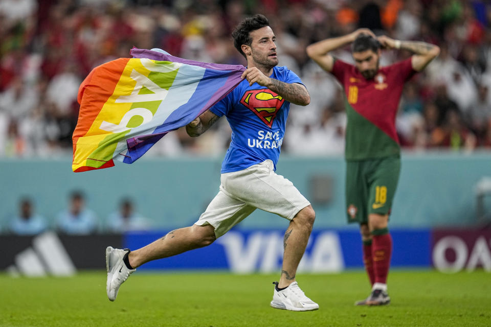 A pitch invader runs across the field with a rainbow flag during the World Cup group H soccer match between Portugal and Uruguay, at the Lusail Stadium in Lusail, Qatar, Monday, Nov. 28, 2022. (AP Photo/Abbie Parr)