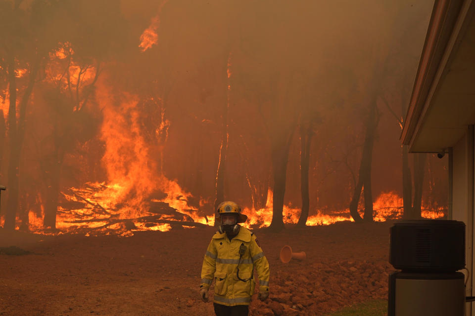 In this photo provided by Department of Fire and Emergency Services, a firefighter attends a fire near Wooroloo, northeast of Perth, Australia, Tuesday, Feb. 2, 2021. An out-of-control wildfire burning northeast of the Australian west coast city of Perth has destroyed dozens of homes and was threatening more. (Evan Collis/DFES via AP)
