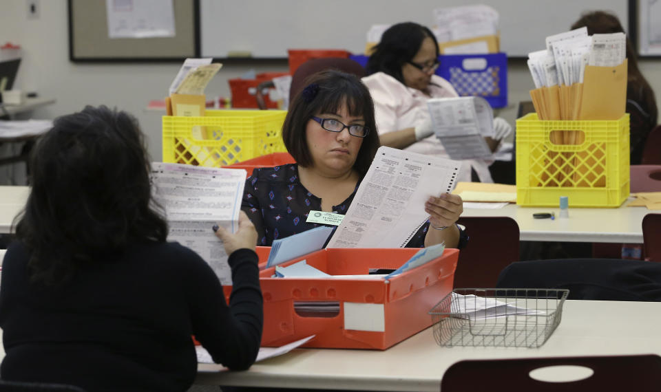 FILE - In this Wednesday, Nov. 12, 2014, file photo, Lydia Harris, a temporary worker at the Sacramento Registrar of Voters, looks over a mail-in ballot before it is sent to be counted in Sacramento, Calif. Over 100,000 mail-in ballots were rejected by election officials in California's March 2020 presidential primary, highlighting a glaring gap in the effort to ensure every vote is counted as a national dispute rages over the integrity of vote-by-mail elections. (AP Photo/Rich Pedroncelli, File)