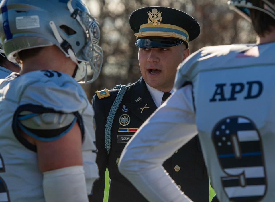 Auburn Police Officer and Army veteran Matt Rodwill talks to Auburn players on the sideline during the annual Tarentino Cup Thanksgiving Day game in, 2023.