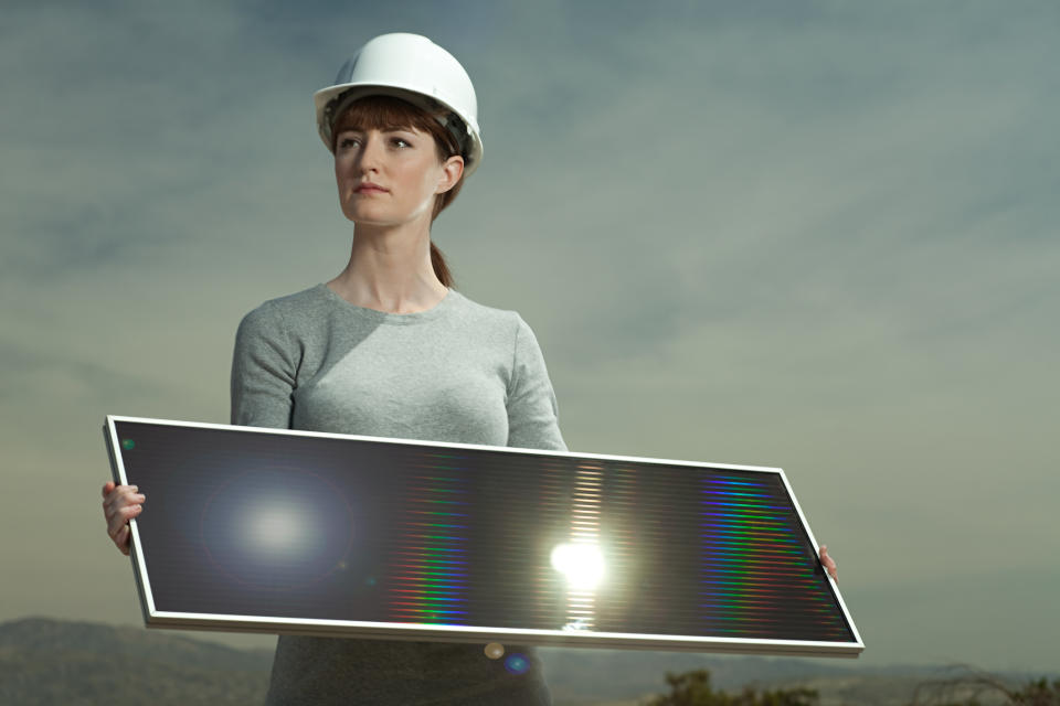 Female construction worker holding a solar panel