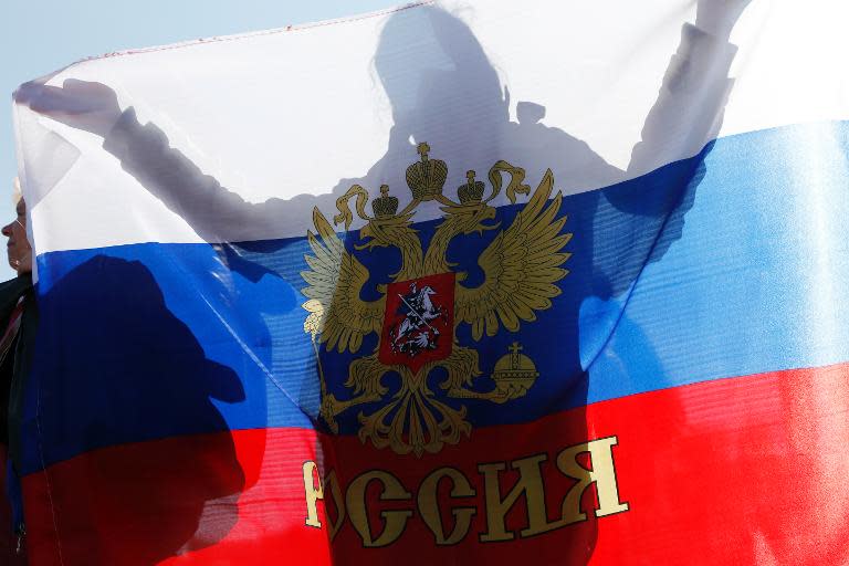 A woman holds a Russian national flag during a rally to support the self-rule "referendums" for the Ukrainian provinces of Donetsk and Lugansk, in central Simferopol on May 11, 2014