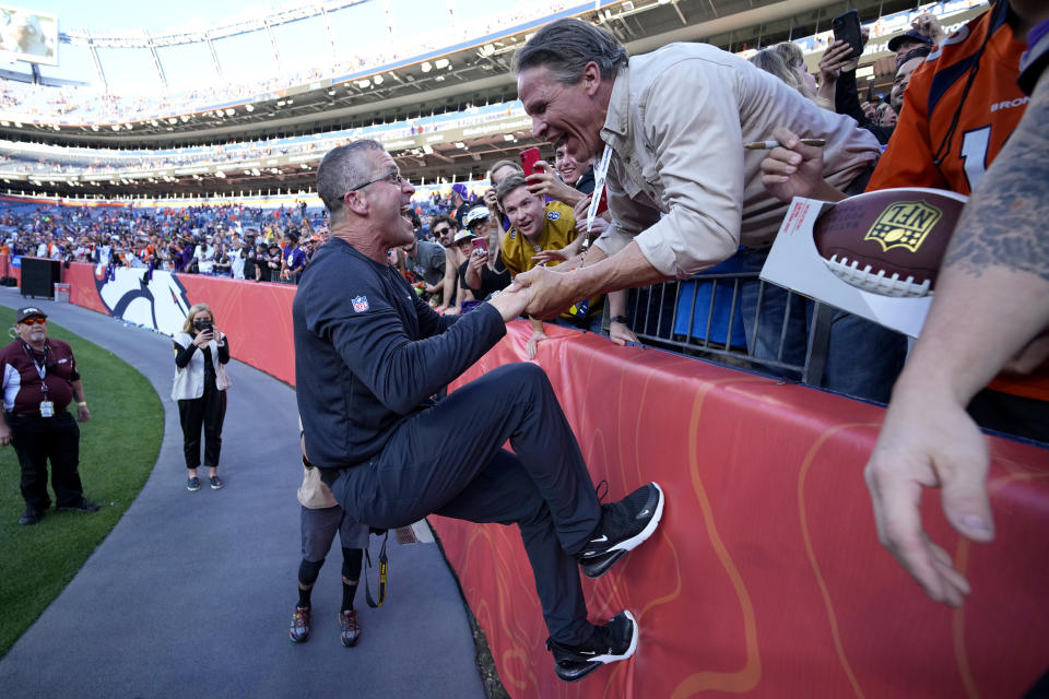 Baltimore Ravens owner Steve Bisciotti pulls head coach John Harbaugh up the wall to celebrate after an NFL football game against the Denver Broncos, Sunday, Oct. 3, 2021, in Denver. The Ravens won 23-7. (AP Photo/David Zalubowski)