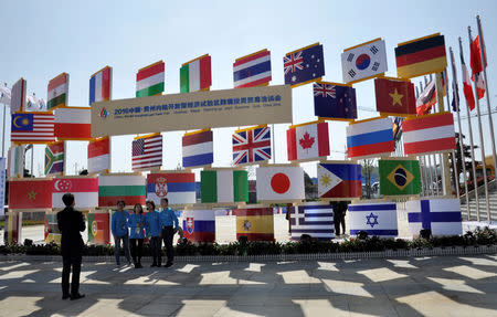 People stand near signboards of a cross-border investment and trade fair in Guiyang, Guizhou Province, China, November 10, 2016. REUTERS/Shu Zhang/Files