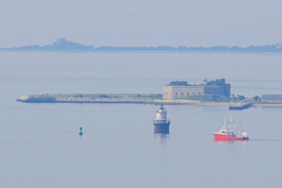 A fishing boat makes its way past Fort Rodman and the Buttler Flats lighthouse as seen from the top of one of the two 80 (260') tall wind turbines in Fairhaven, MA.