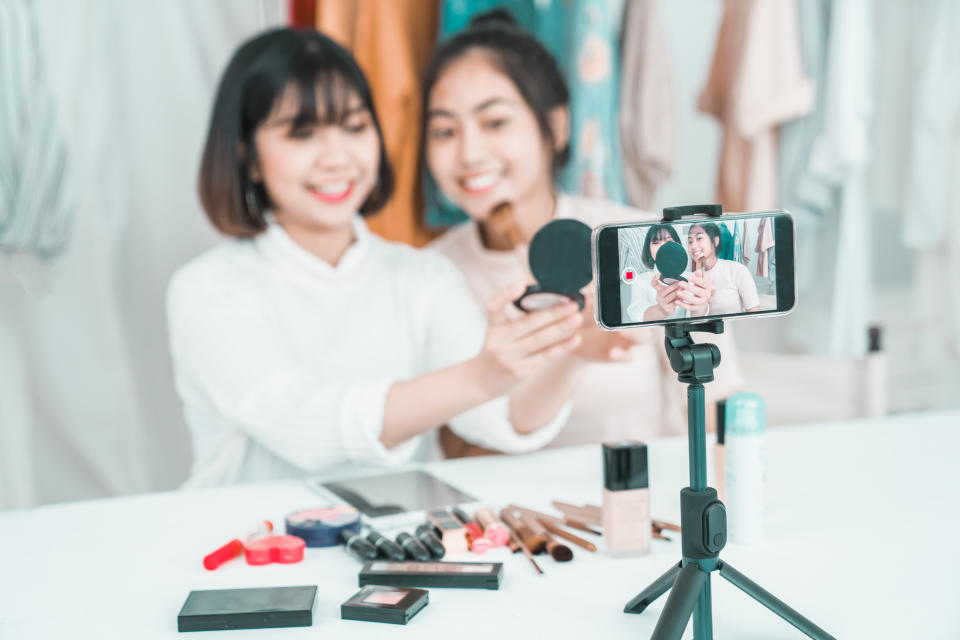 Two young women use social media to demonstrate cosmetics. (Photo: Getty)