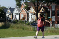 Eugenia Rodriguez walks in Chicago's La Villita Park, Thursday, July 1, 2021. She is required to get out for a walk or a run every morning to keep her varicose veins active and hasn't been eligible for insurance coverage after overstaying a visitor visa from Mexico. Rodriguez used to wake up every two or three hours at night to check on her mother in their Chicago home. Since getting insurance through the Illinois program, her mother has proper medications. (AP Photo/Shafkat Anowar)