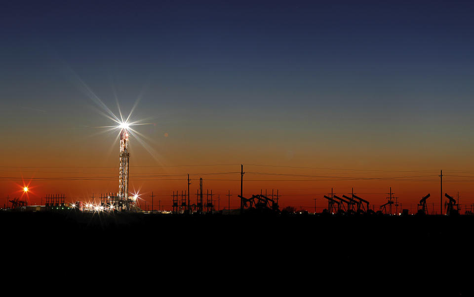 In this Thursday, April 2, 2020 photo, an oil rig lights up the horizon on the outskirts of Midland, Texas after a late sunset. (Odessa American/Eli Hartman)