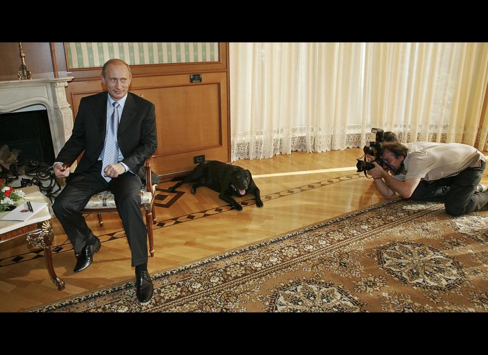 Putin awkwardly sits and smiles as photographers try to take photos of his dog Koni at the president's residence in Sochi, Russia, on Aug. 18, 2005.