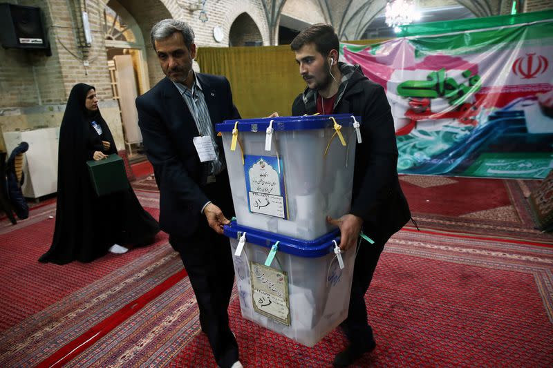 Poll workers carry full ballot boxes after the parliamentary election voting time ended in Tehran