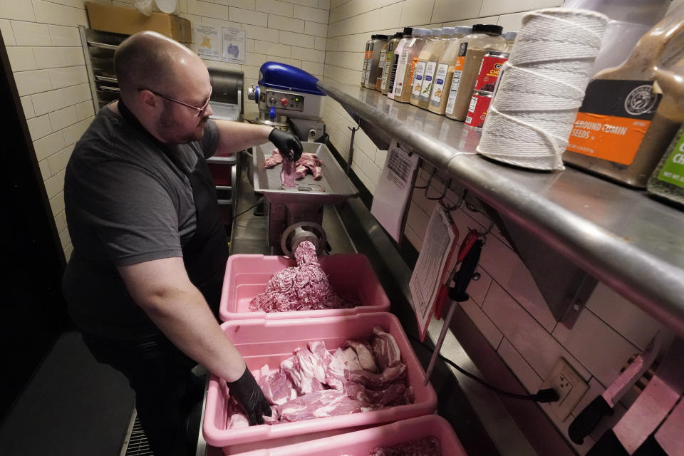 James Barlow prepares sausages at Von Elrod's Beer Hall And Kitchen on June 7, 2022, in Nashville, Tenn. For the restaurant, located across the street from Nashville's minor league baseball stadium that sees big crowds in the summer, both inflation and the worker shortage have sent costs skyrocketing. Small businesses that depend on summer crowds and tourism are hoping for a bustling summer this year, boosted by pent up demand after more than two years of the pandemic. (AP Photo/Mark Humphrey)