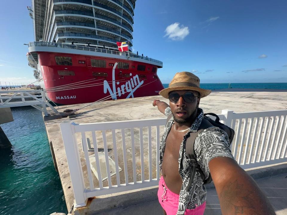 J. Alexander selfie posing in front of a Virgin cruise ship and pointing at it.