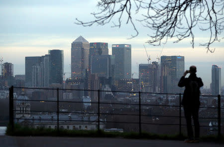 FILE PHOTO: A man takes a photograph of the Canary Wharf financial district from Greenwich Park in London, Britain, January 22, 2017. REUTERS/Hannah McKay/File Photo