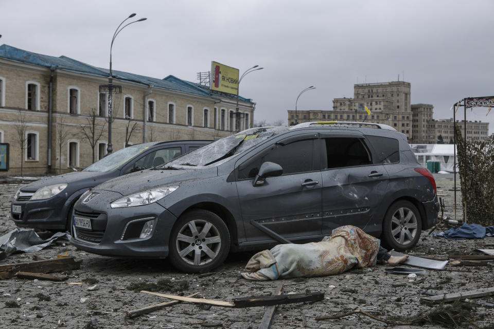 The body of a victim lies next to damaged cars in the central square following shelling of the City Hall building in Kharkiv, Ukraine, Tuesday, March 1, 2022. Russia on Tuesday stepped up shelling of Kharkiv, Ukraine's second-largest city, pounding civilian targets there. Casualties mounted and reports emerged that more than 70 Ukrainian soldiers were killed after Russian artillery recently hit a military base in Okhtyrka, a city between Kharkiv and Kyiv, the capital. (AP Photo/Pavel Dorogoy)