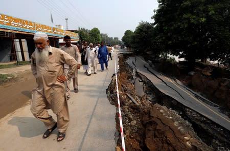 People walk along a road damaged during an earthquake in Jatlan, Mirpur