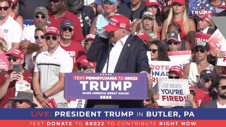 A screen grab captured from a video shows Republican presidential candidate former President Donald Trump clasping his right ear after gunshots were reported during a rally.