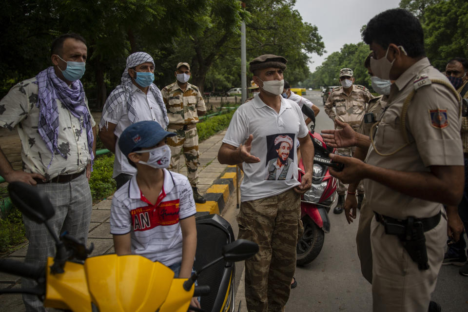 An Afghan refugee wearing a T-shirt with the picture of slain anti-Taliban fighter Ahmad Shah Massoud speaks to an Indian police officer after they were denied permission to protest outside Pakistan embassy in New Delhi, India, Thursday, Sept. 9, 2021. (AP Photo/Altaf Qadri)