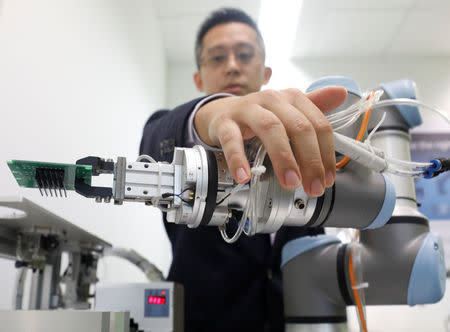 A Universal Robots employee demonstrates how a model of their industrial robot arms works in Singapore March 3, 2017. Picture taken March 3, 2017. REUTERS/Edgar Su