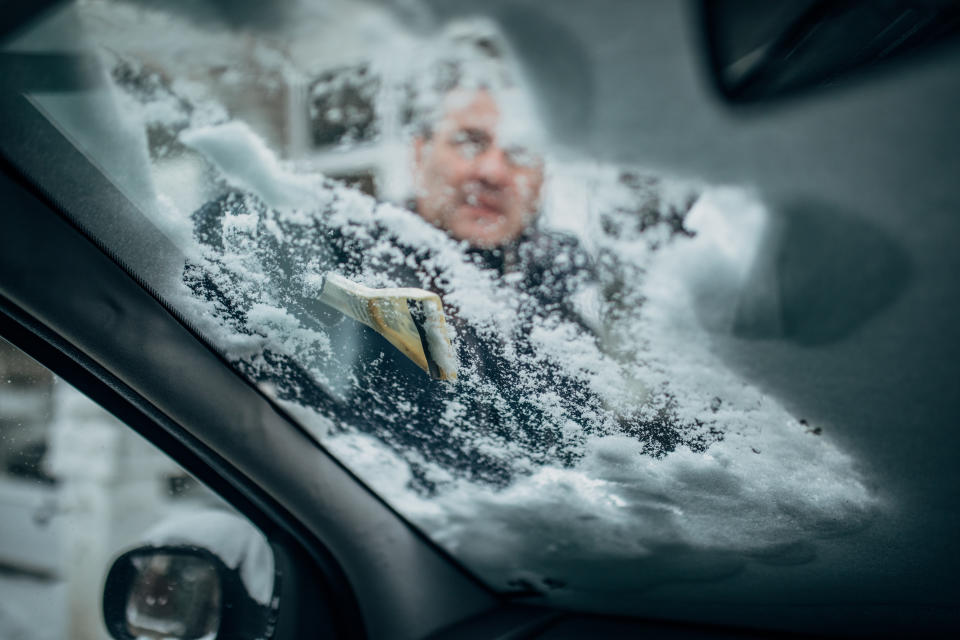 One man, cleaning his snow covered car in front yard.