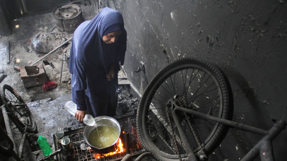 A displaced Palestinian woman uses water as she cooks in Jabalia refugee camp, northern Gaza. - Mahmoud Issa/Reuters