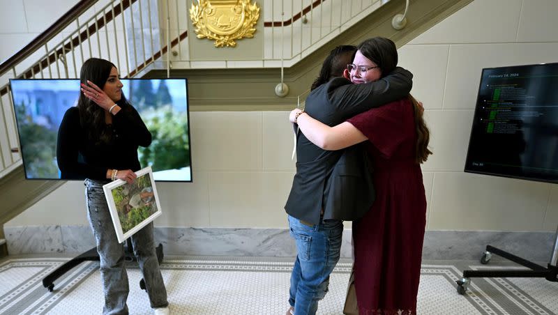 Karl Obray hugs Liddy Johnson, who also testified in committee. His wife, Brittney Obray, is at the left with a photo of their son Dexton, who committed suicide due to social media influences, after a House Judiciary Committee hearing as Rep. Jordan Teuscher, R-South Jordan, presents HB464, Social Media Regulation Act Amendments, at the Capitol in Salt Lake City on Wednesday, Feb. 14, 2024.