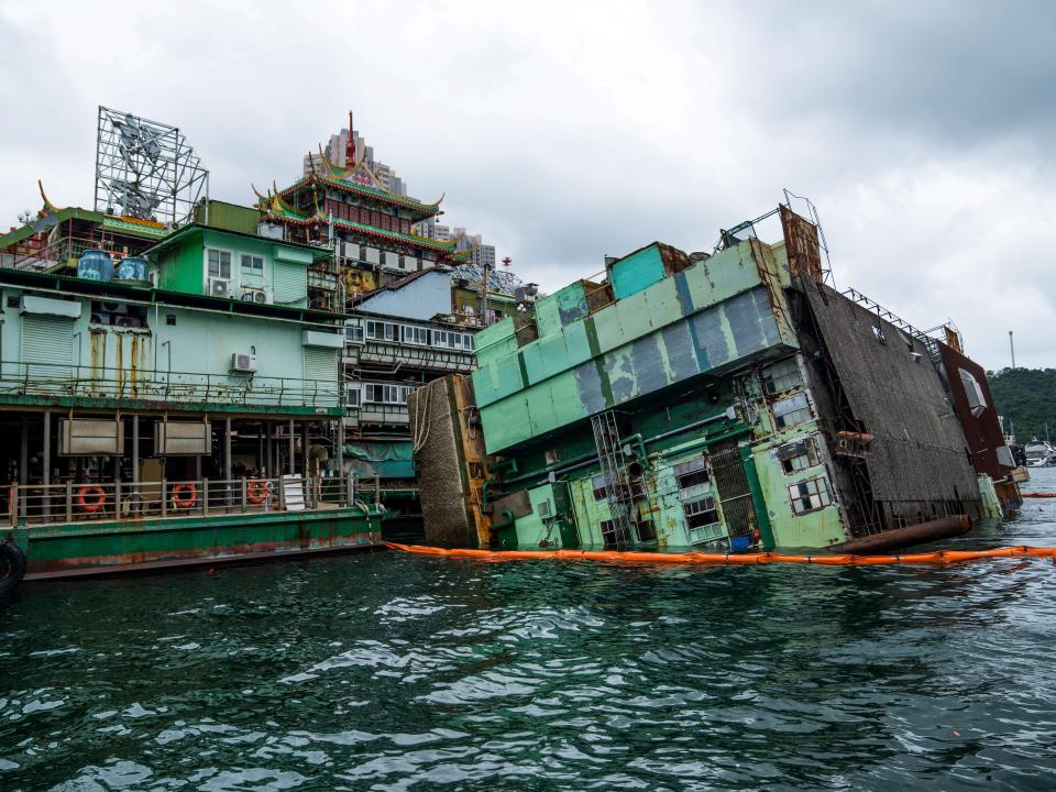 This photo taken on June 13, 2022 shows a kitchen barge (R) attached to the main section of the Jumbo Floating Restaurant sitting on its side after capsizing, in the typhoon shelter near Aberdeen on the south side of Hong Kong island. - Local newspapers have reported the restaurant, which has been closed due to Covid-19 and lack of tourists since 2020, will exit the city after its owner suffered extensive losses. (Photo by Bertha WANG / AFP) (Photo by BERTHA WANG/AFP via Getty Images)