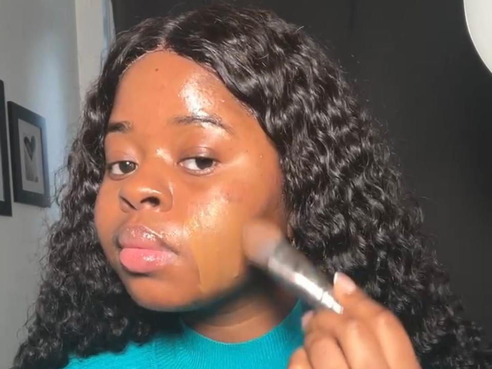 The writer brushes a foundation that matches her skin tone on her face