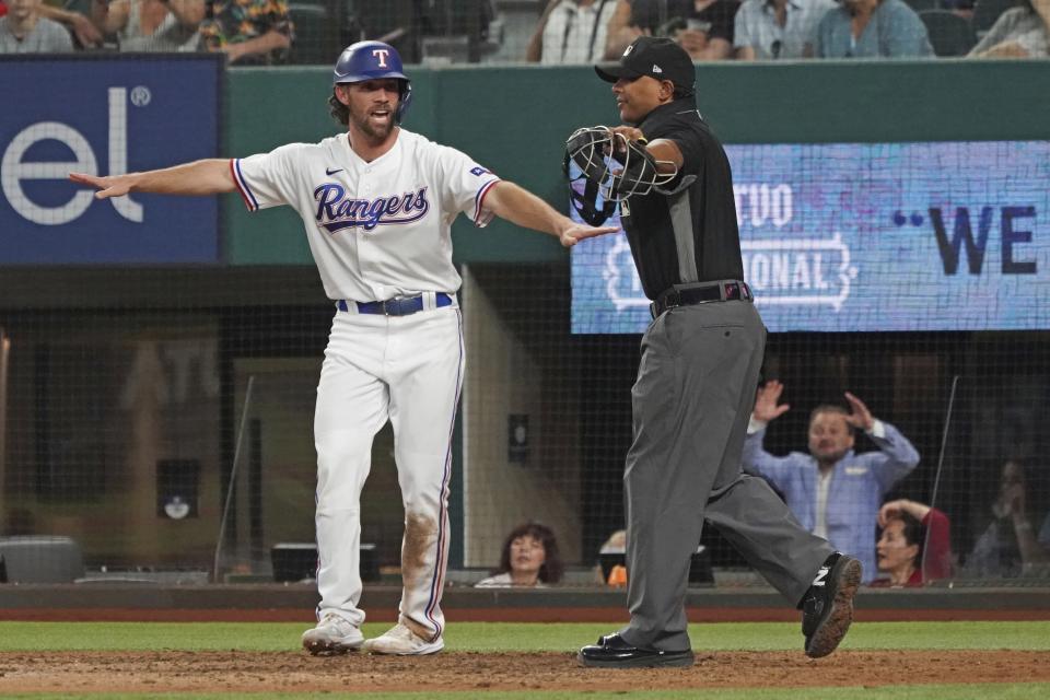 Texas Rangers base runner Charlie Culberson signals himself safe at home as he scores a run against the Seattle Mariners in the eighth inning of a baseball game Saturday, May 8, 2021, in Arlington, Texas. (AP Photo/Louis DeLuca)