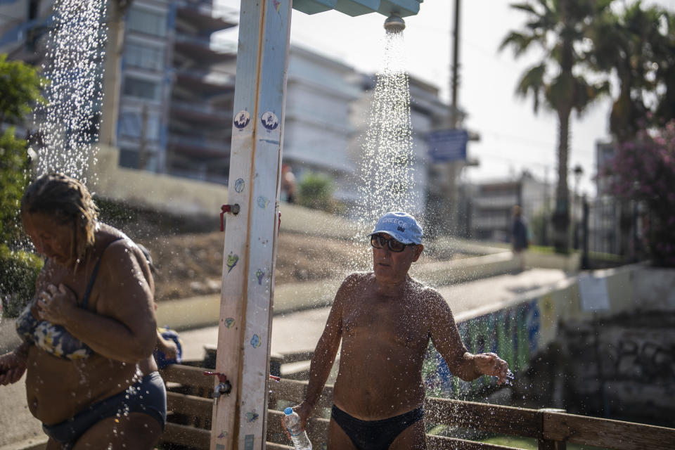 Bathers take a shower during a hot day at Alimos beach near Athens, Friday, July 14, 2023. Temperatures were starting to creep up in Greece, where a heatwave was forecast to reach up to 44 degrees Celsius in some parts of the country over the weekend. (AP Photo/Petros Giannakouris)