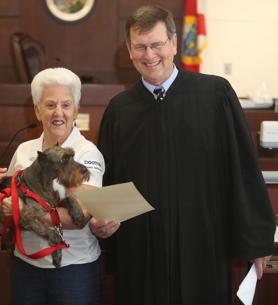 Joanne Taylor holds her dog "Sir Smudge" and gets a photo taken with Circuit Judge James Hankinson on Thursday. Thirteen  therapy dogs were sworn in at the courthouse on Thursday, April 18, 2013. The dogs are used to help abused children deal with a traumatic  experience. The first use of a therapy dog in Leon County was in 2007. The program was initially started to comfort and  support children testifying as victims in violent crimes and has expanded to include other crimes. To date, 55 cases have used therapy dogs to support the 2nd Judicial Court.