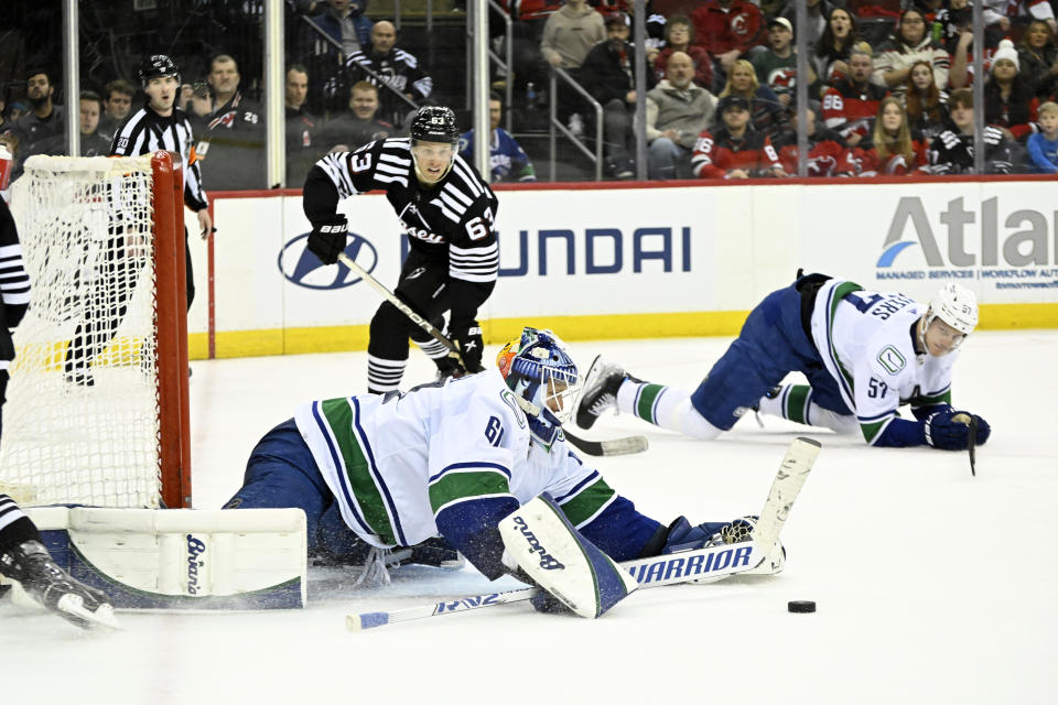 CORRECTS MONTH TO FEB. NOT JAN. - Vancouver Canucks goaltender Collin Delia, front left, stops the puck as New Jersey Devils left wing Jesper Bratt (63) watches on during the second period of an NHL hockey game, Monday, Feb. 6, 2023, in Newark, N.J. (AP Photo/Bill Kostroun)