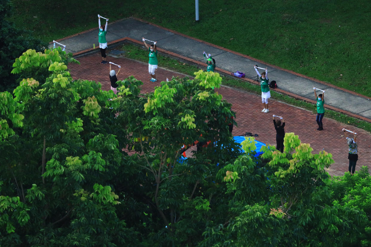 People wearing protective mask exercise at a park on June 2, 2021 in Singapore. Singapore enters a month long heightened alert from May 16 to June 13 to curb the spread of COVID-19 cases in the local community. New restrictions on movements and activities have been introduced such as limiting social interaction to two, prohibiting dining out and a reduced operating capacity at shopping malls, offices and attractions. (Photo by Suhaimi Abdullah/NurPhoto via Getty Images)