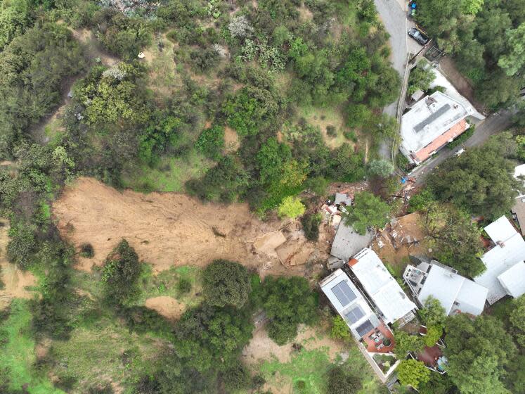 Los Angeles, CA - February 05: An aerial view of a Beverly Crest home that was pushed off it's foundation by a mudslide early Monday morning near Beverly Glen Boulevard. No one was home when the mudslide occurred. Caribou Lane Resident Travis Longcore said he and neighbors evacuated themselves after hearing a loud rumbling sound around 2 a.m. Photographers record the scene and So Cal Gas workers work to make sure there are no gas leaks. The debris completely covers Caribou Lane and caused extensive damage to several others. Rocks, plywood and a piano were washed out of the home and turned upside down on the street. An atmospheric river unleashed heavy rain in Southern California Monday, Feb. 5, 2024. (Allen J. Schaben / Los Angeles Times)
