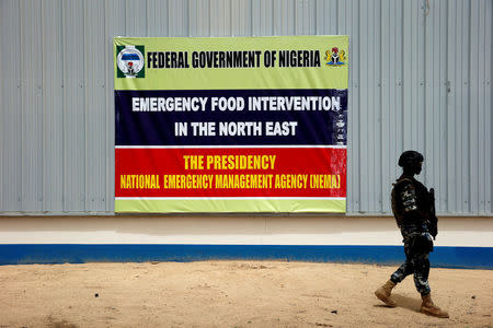 FILE PHOTO: A soldier walks past a banner pasted on a warehouse where food and relief materials for the internal displaced persons are stored on the outskirts of Nigerian city of Maiduguri, Nigeria June 8, 2017. REUTERS/Akintunde Akinleye/File Photo