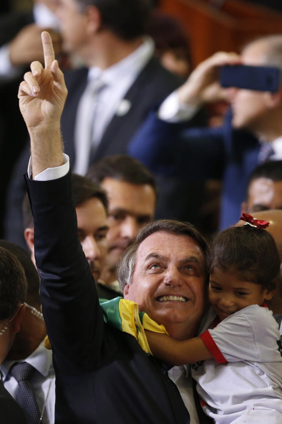 Brazil's President Jair Bolsonaro holds a child during a Christmas celebration with staff and students at the Planalto Presidential Palace, in Brasilia, Brazil, Thursday, Dec. 19, 2019. (AP Photo /Eraldo Peres)