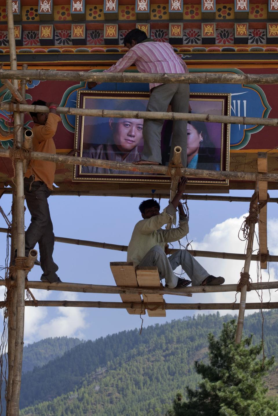 Men hang a portrait of Bhutan's king and fiancee on an archway in Bhutan's capital Thimphu