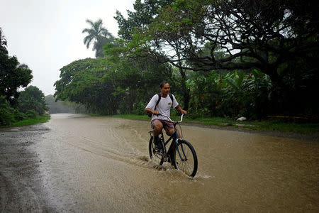 A man rides a bicycle down a flooded road as Subtropical Storm Alberto passes by the west coast of Cuba, in Bahia Honda, Cuba, May 26, 2018. REUTERS/Alexandre Meneghini