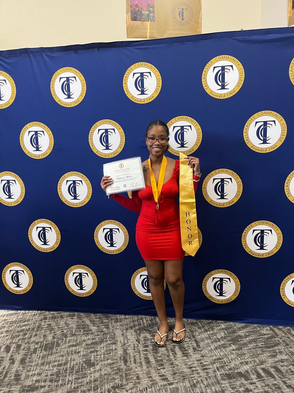 TCC graduating student Makaira Skeete holds up a certificate and a stole from TCC's Honors Program.