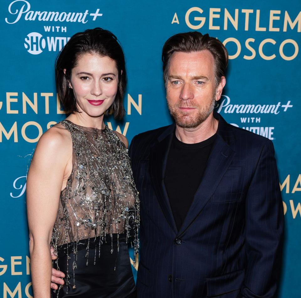 Ewan McGregor and Mary Elizabeth Winstead posing together at an event. She wears a beaded top and skirt; he sports a pinstripe suit