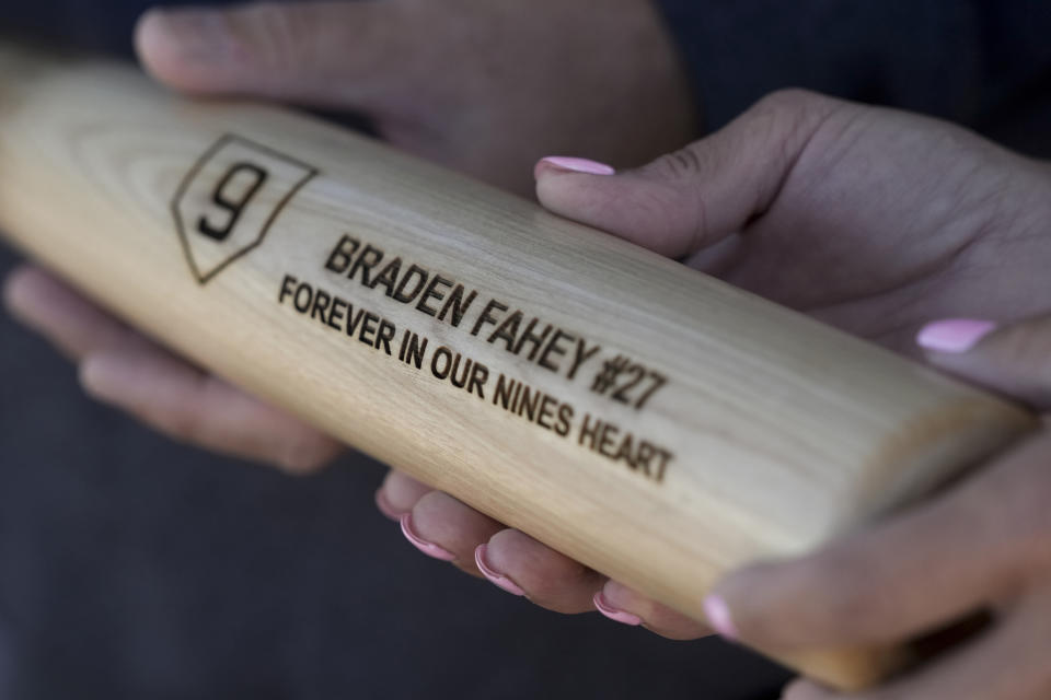 Padrig and Gina Fahey hold a bat dedicated to their son, Braden, by his baseball travel team Wednesday, Sept. 6, 2023, in California. Braden, 12, collapsed at a football practice last August and died of a malformed blood vessel in the brain. (AP Photo/Godofredo A. Vásquez)