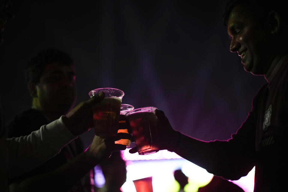 FILE - People drink beers as they watch in a giant screen at the fan zone the World Cup group A soccer match between Qatar and Ecuador being played at the Al Bayt stadium in Al Khor, in Doha, Qatar, Sunday, Nov. 20, 2022. (AP Photo/Francisco Seco, File)