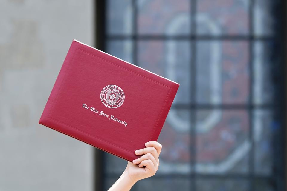 Ohio State doctor of pharmacy candidate Shirley Chen of Cleveland, holds up a diploma while taking photos in front of Ohio Stadium ahead of Sunday’s commencement ceremony. Approximately 12,000 are expected to receive degrees during the graduation ceremony.