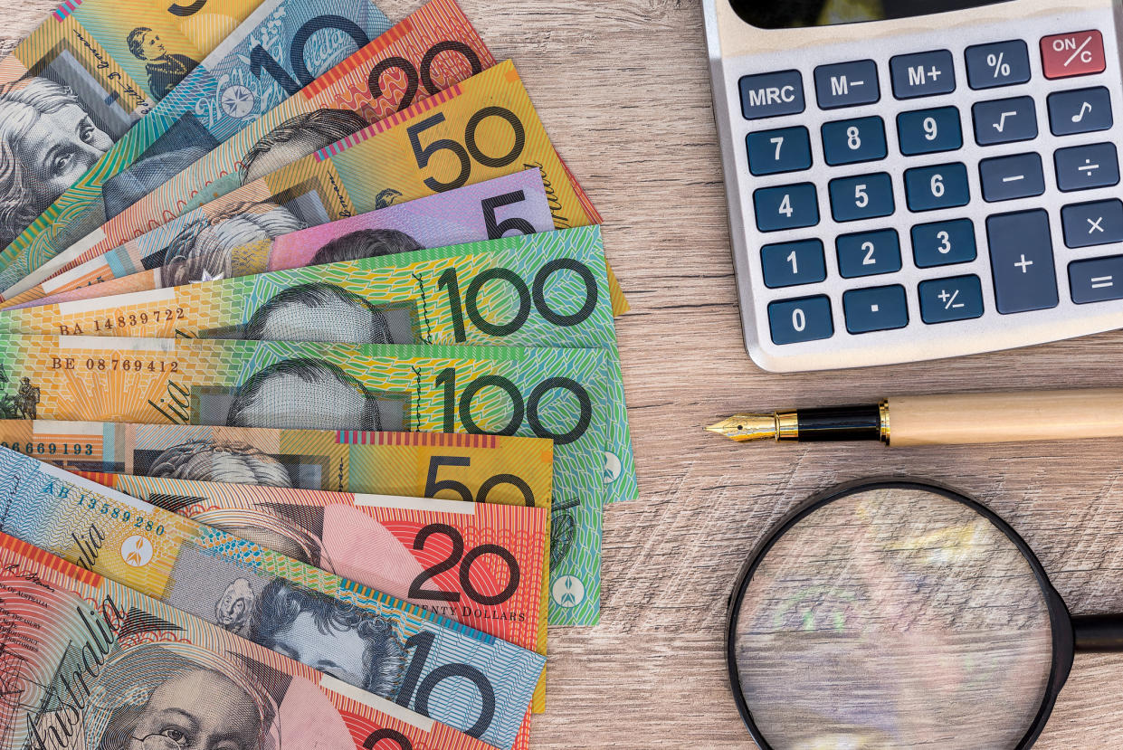 Australian dollars with calculator, pen and magnifier used to file tax return. Image: Getty