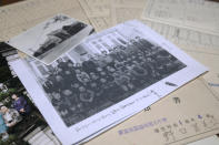 A photograph of a school building and a photocopy of a class picture on top of the report cards of Fumie Sato's first to sixth grades from the elementary school in Manchuria, China, are seen Friday, Aug. 7, 2020, at her home in Yokohama, Japan. Hours after Sato heard Emperor Hirohito's Aug. 15 radio speech declaring Japan's defeat at her school ground in Manchuria, China, she had to be prepared for honorable suicide with her family, though her father decided his family must live. Two years later she almost became an orphan when her little sister died of illness after their mother and little brother took an earlier boat back to Japan. (AP Photo/Kiichiro Sato)