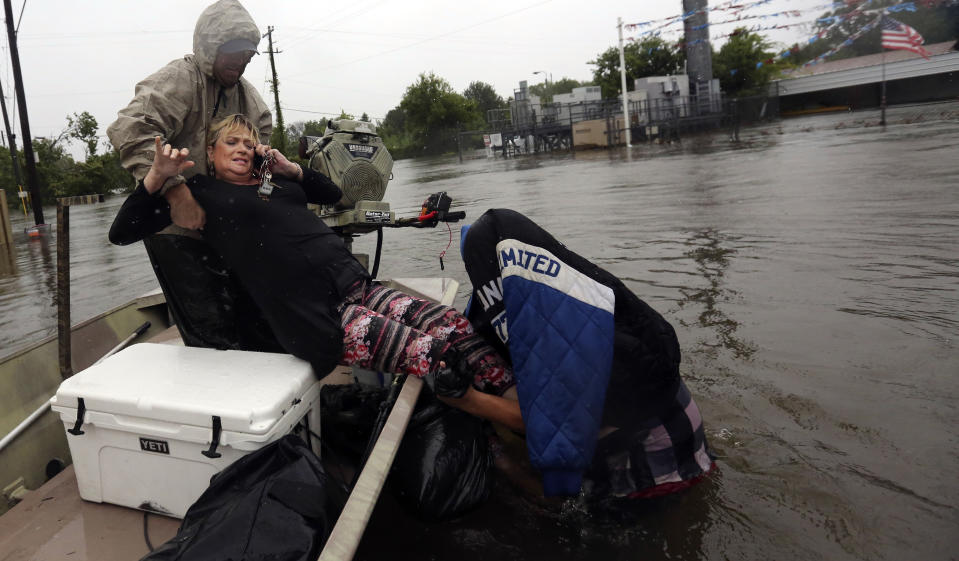 Ein Unbekannter zieht Rhonda Worthington in sein Boot, nachdem die Frau mit ihrem Auto von den Wassermassen überrascht worden war. (Bild: AP Photo/LM Otero)