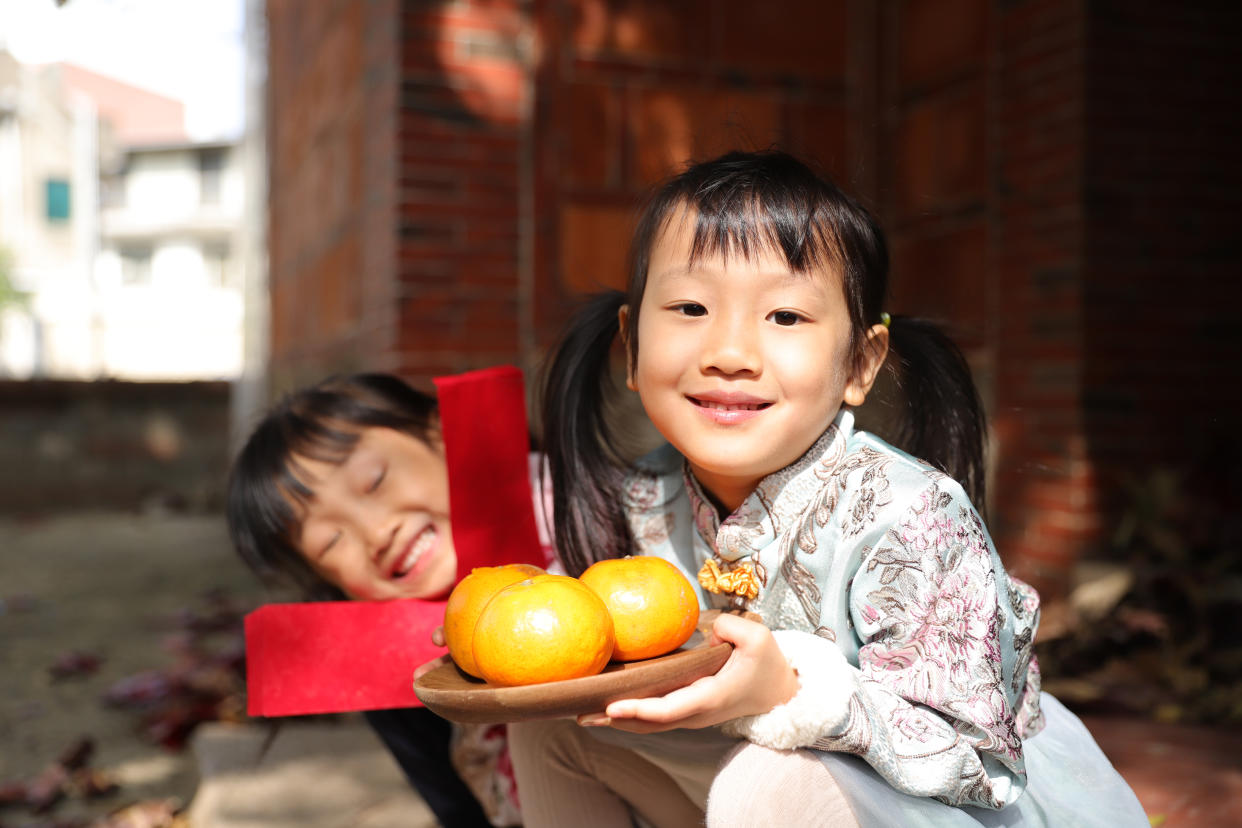 Two children wearing cheongsam and holding oranges. (PHOTO: Getty Images)