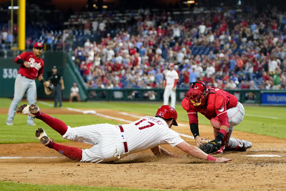 Philadelphia Phillies' Rhys Hoskins, left, is tagged out at home by Cincinnati Reds catcher Austin Romine after trying to score on a double by J.T. Realmuto during the seventh inning of a baseball game, Wednesday, Aug. 24, 2022, in Philadelphia. (AP Photo/Matt Slocum)