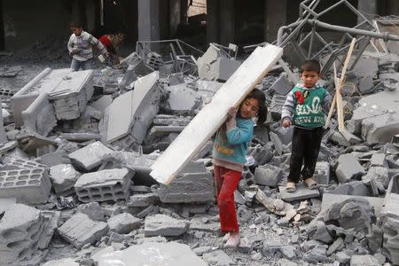 Children collect items from among the debris of a school for the deaf and mute, destroyed in what activists said were overnight U.S.-led air strikes against the Islamic State, in Raqqa November 24, 2014. REUTERS/Nour Fourat